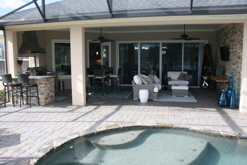 Norstone Aztec Stacked Stone Veneer used on the outdoor kitchen and an outdoor feature wall in a nicely designed outdoor living space opening up to a screened in pool